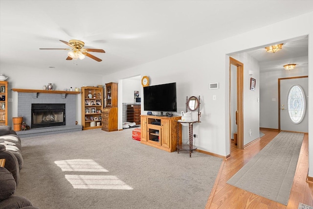 living room with a fireplace, light hardwood / wood-style floors, and ceiling fan