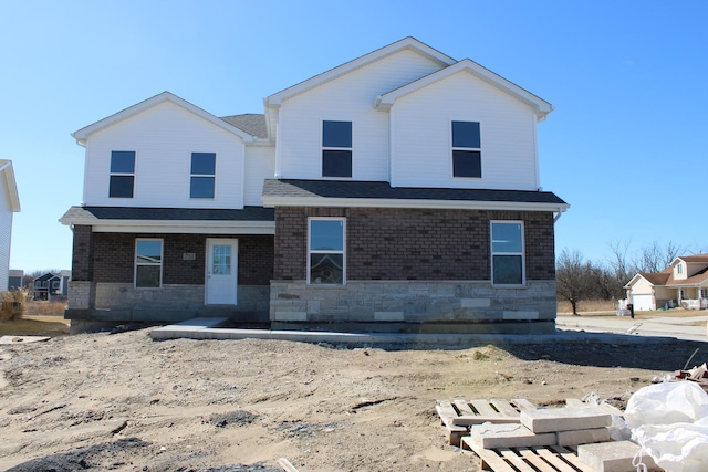 view of front of property with stone siding, roof with shingles, and brick siding