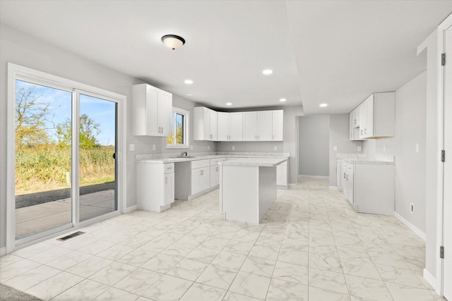 kitchen featuring white cabinets, a kitchen island, and sink