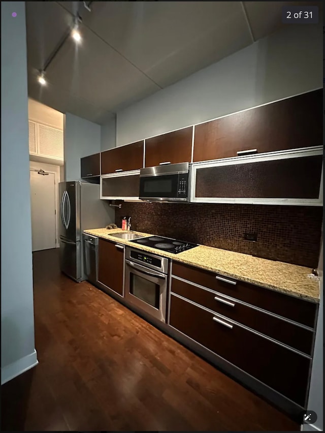 kitchen featuring dark brown cabinetry, tasteful backsplash, dark wood-type flooring, and black appliances