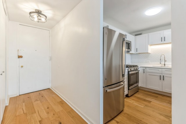 kitchen featuring white cabinets, light hardwood / wood-style floors, sink, and appliances with stainless steel finishes