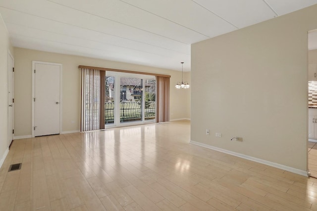 empty room featuring light hardwood / wood-style flooring and a chandelier