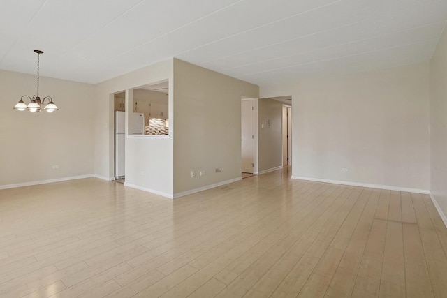 unfurnished room with light hardwood / wood-style flooring and an inviting chandelier