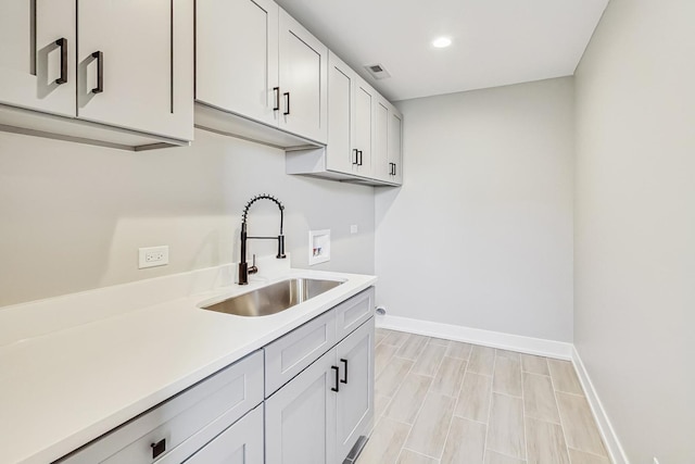 laundry room featuring sink, hookup for a washing machine, and cabinets