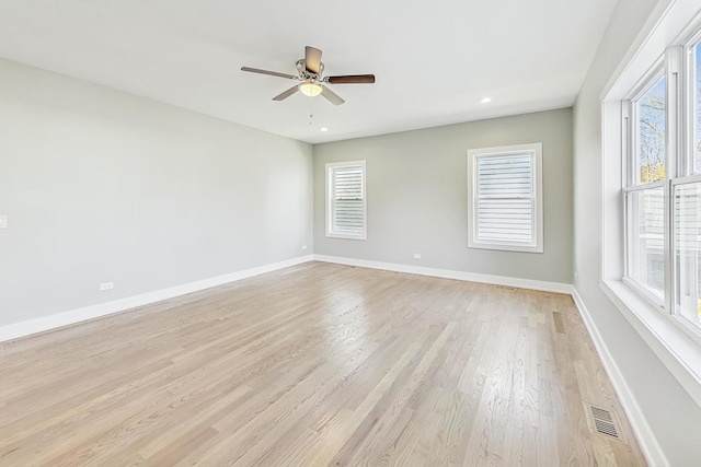 empty room with ceiling fan, light wood-type flooring, and plenty of natural light