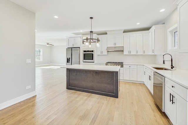 kitchen featuring sink, stainless steel appliances, white cabinetry, and hanging light fixtures