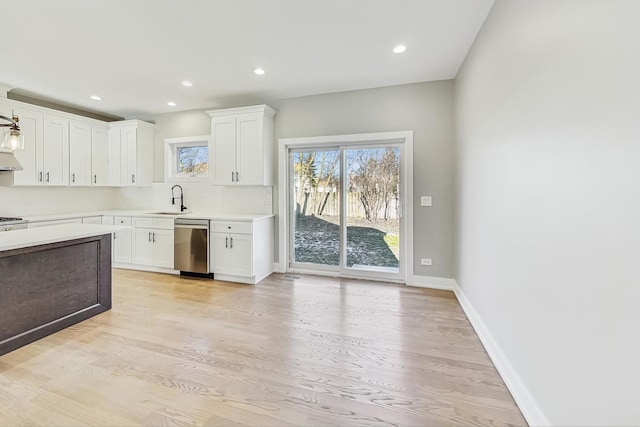 kitchen featuring sink, stainless steel dishwasher, light hardwood / wood-style floors, and white cabinetry