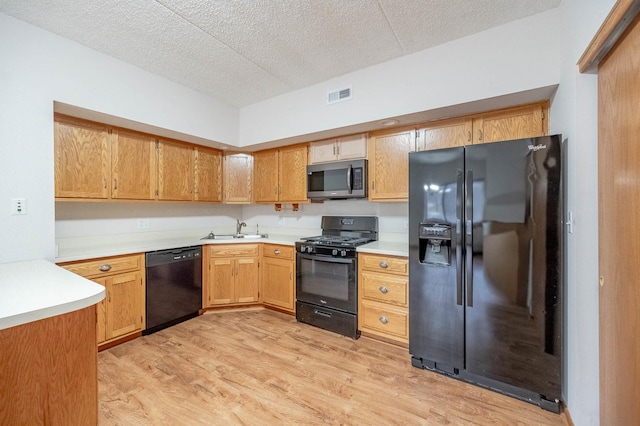 kitchen with sink, black appliances, a textured ceiling, and light wood-type flooring