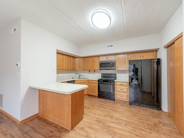 kitchen with black appliances, sink, a textured ceiling, light hardwood / wood-style floors, and kitchen peninsula