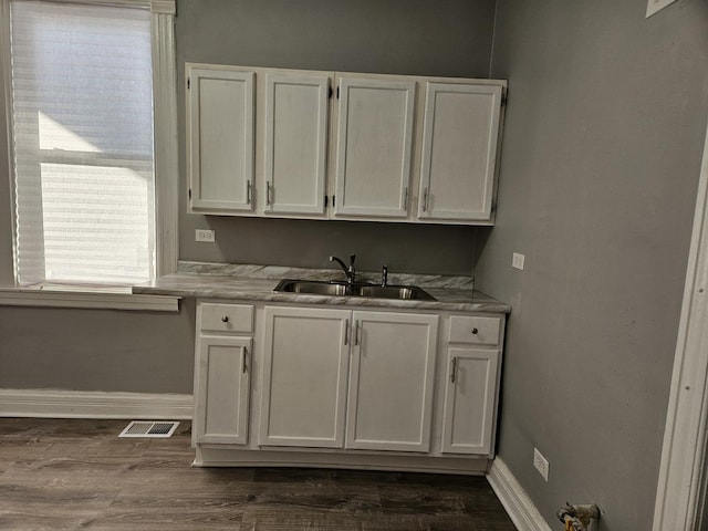 interior space with sink, white cabinets, and dark wood-type flooring