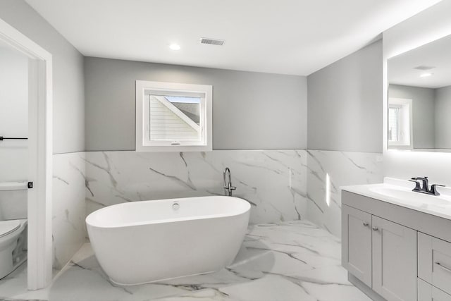 bathroom featuring vanity, toilet, tile walls, and a bathing tub