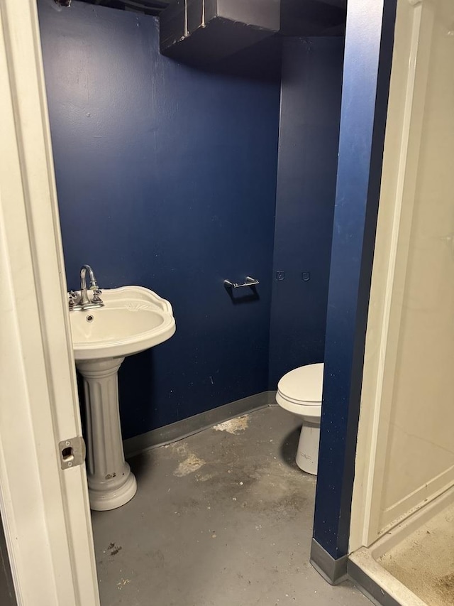 bathroom with toilet and concrete flooring