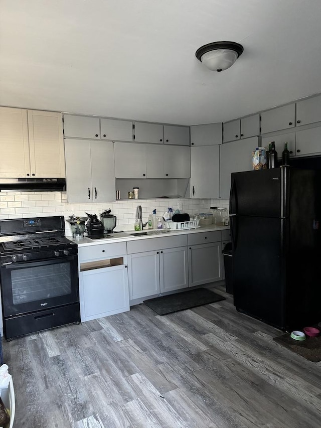 kitchen featuring black appliances, decorative backsplash, light hardwood / wood-style floors, and sink