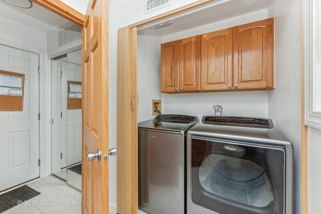 laundry area with washer and clothes dryer, light tile patterned flooring, and cabinets