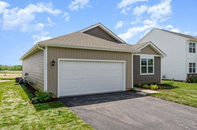 exterior space with a lawn, a garage, and central air condition unit