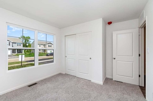 unfurnished bedroom featuring light carpet and a closet