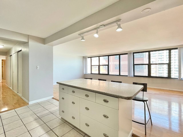 kitchen featuring white cabinets, light tile patterned floors, a kitchen island, and a healthy amount of sunlight