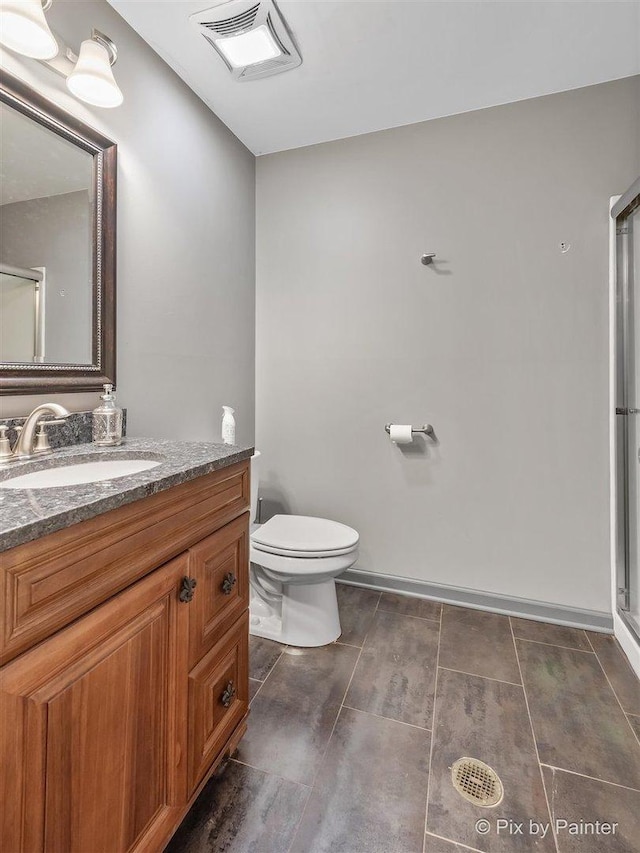 bathroom with a shower with door, vanity, and toilet