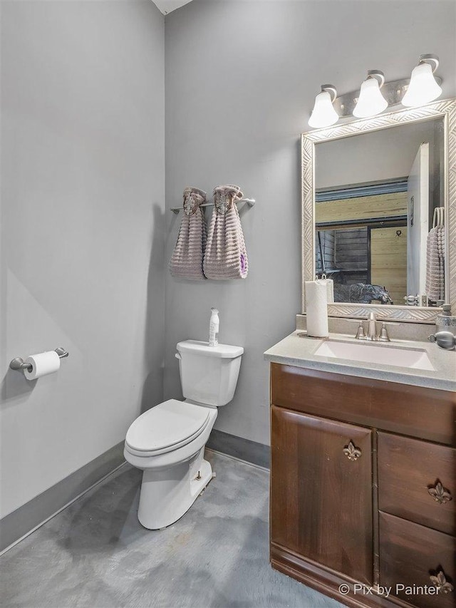 bathroom with vanity, toilet, and concrete flooring