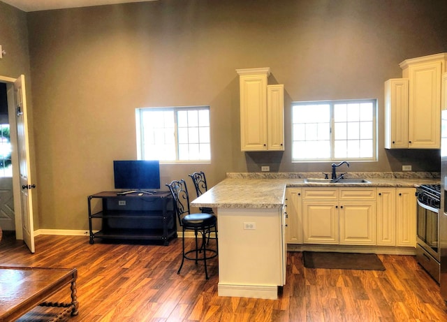 kitchen featuring a kitchen breakfast bar, stainless steel range with gas cooktop, white cabinetry, and sink