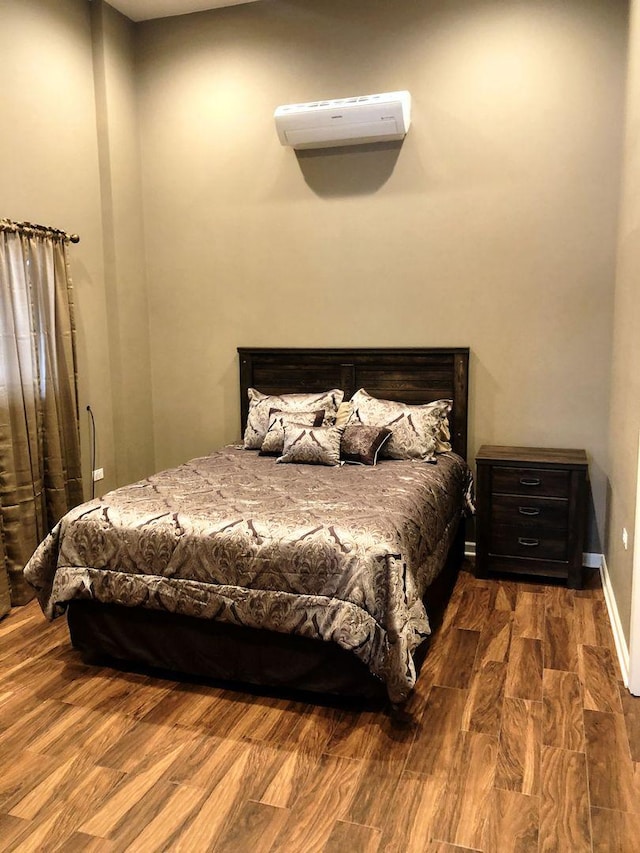 bedroom with wood-type flooring and a wall mounted AC