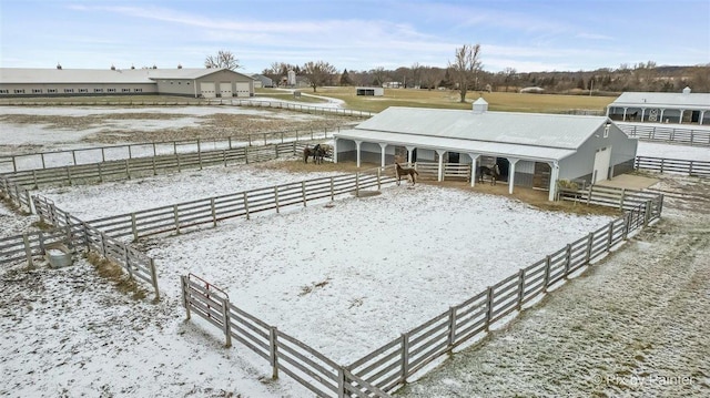 snow covered house featuring a rural view and an outdoor structure