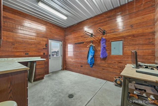 interior space featuring concrete flooring, electric panel, and wooden walls