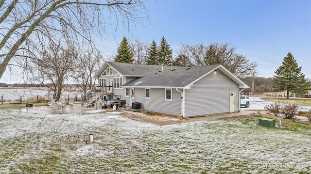 snow covered rear of property featuring central AC unit