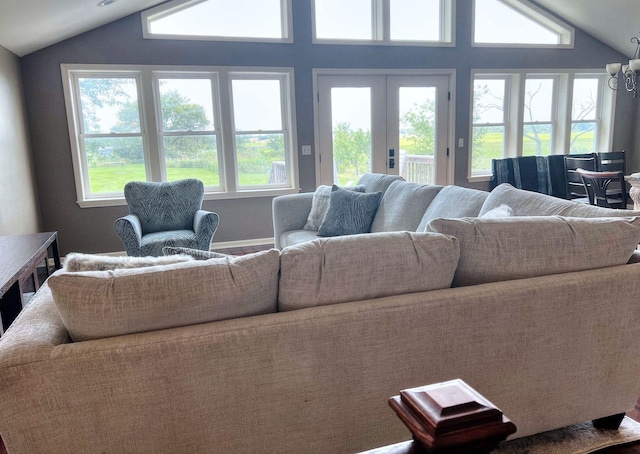 living room with french doors, a chandelier, and vaulted ceiling