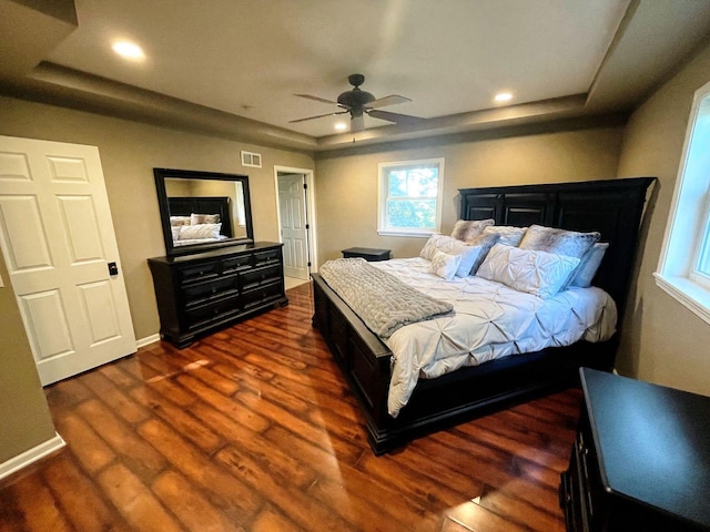 bedroom with dark hardwood / wood-style flooring, a raised ceiling, and ceiling fan