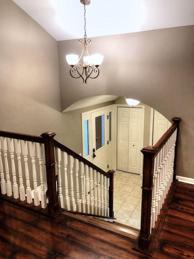 staircase featuring hardwood / wood-style flooring and an inviting chandelier