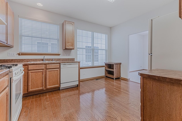 kitchen featuring white appliances, sink, and light hardwood / wood-style flooring