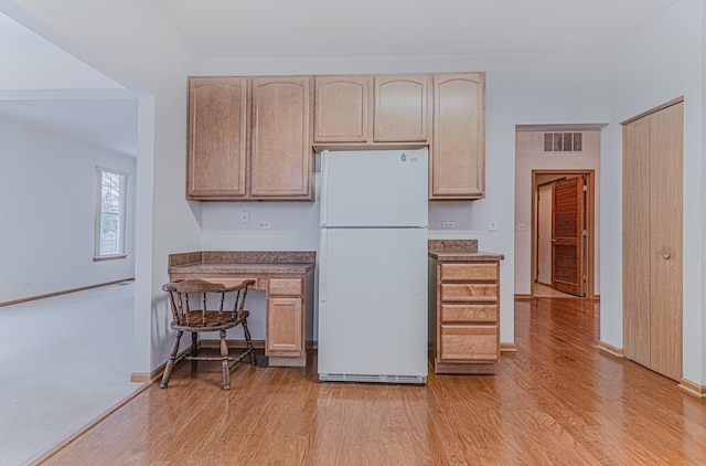 kitchen with light brown cabinetry, light wood-type flooring, and white fridge