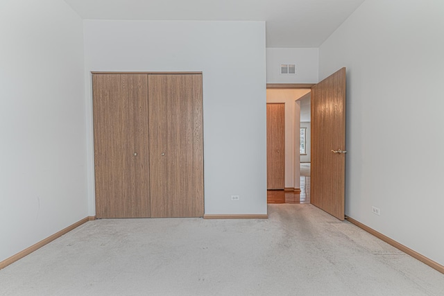 unfurnished bedroom featuring light carpet and a closet