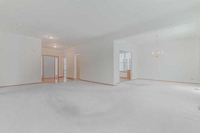 carpeted spare room featuring an inviting chandelier