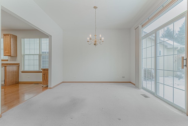 interior space featuring a healthy amount of sunlight, light colored carpet, and an inviting chandelier