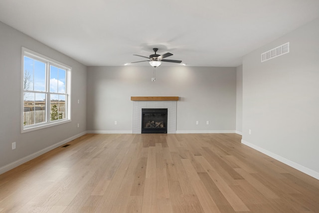 507 Wheatley Dr, Mahomet, IL 61853 - unfurnished living room with visible vents, baseboards, a fireplace, ceiling fan, and light wood-type flooring