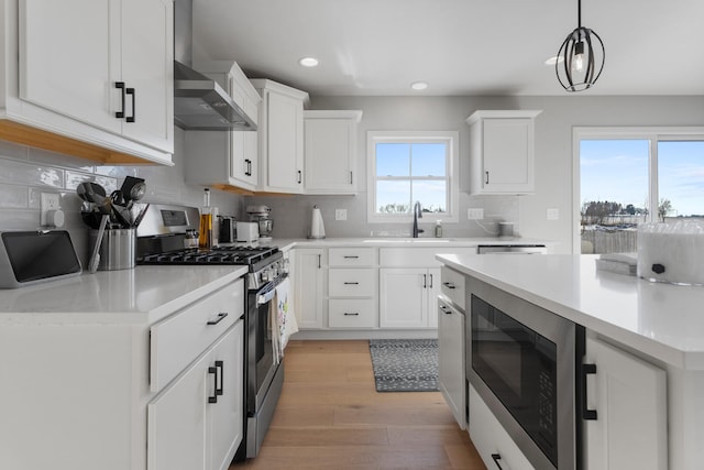 kitchen with decorative light fixtures, stainless steel gas range, built in microwave, and white cabinetry