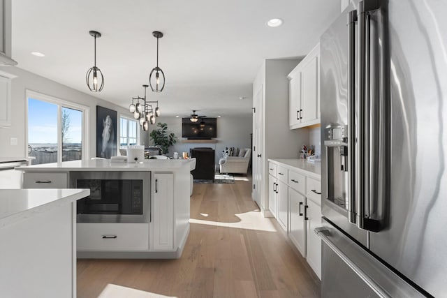 kitchen with light hardwood / wood-style floors, built in microwave, pendant lighting, white cabinets, and high end fridge