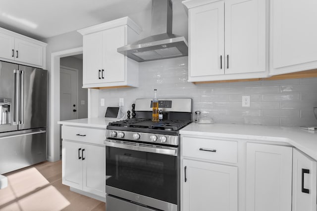 kitchen featuring stainless steel appliances, light wood-type flooring, white cabinets, wall chimney range hood, and backsplash