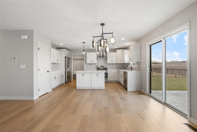 507 Wheatley Dr, Mahomet, IL 61853 - kitchen with stainless steel appliances, tasteful backsplash, a sink, light wood-style floors, and an inviting chandelier