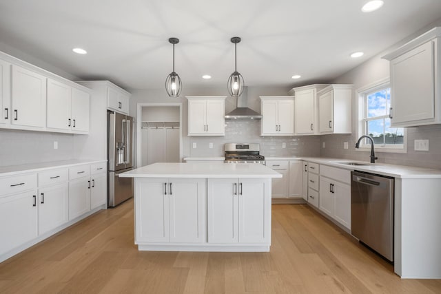 507 Wheatley Dr, Mahomet, IL 61853 - kitchen with stainless steel appliances, a center island, a sink, light wood-style floors, and wall chimney range hood