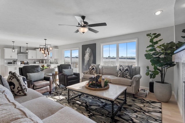 living room with ceiling fan with notable chandelier and light wood-type flooring