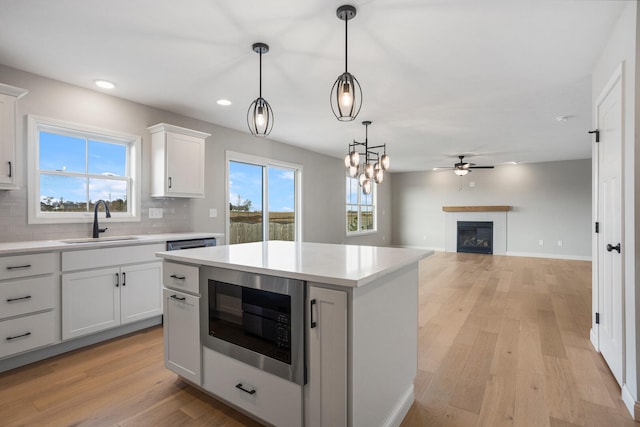 507 Wheatley Dr, Mahomet, IL 61853 - kitchen featuring light countertops, light wood-type flooring, a sink, built in microwave, and a glass covered fireplace