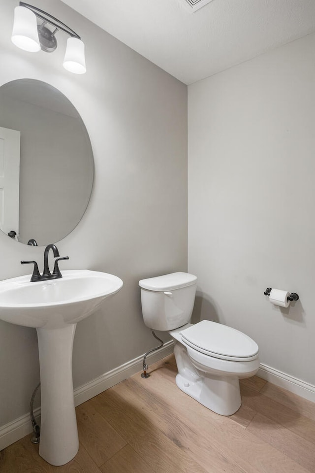 507 Wheatley Dr, Mahomet, IL 61853 - bathroom featuring baseboards, wood finished floors, toilet, and a sink