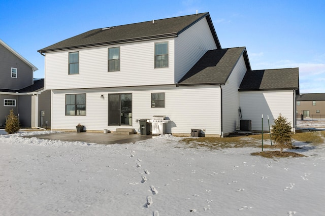 snow covered back of property featuring central AC