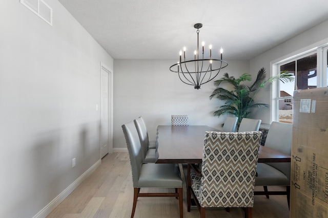 dining area with light hardwood / wood-style floors and a chandelier