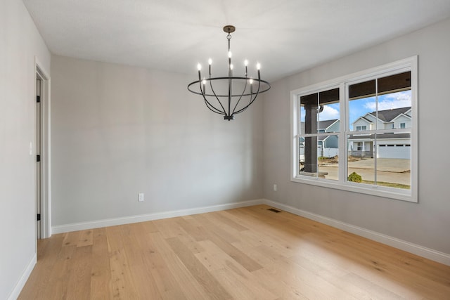 507 Wheatley Dr, Mahomet, IL 61853 - empty room featuring a notable chandelier, baseboards, and light wood-type flooring
