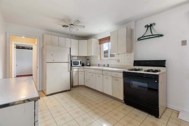 kitchen featuring black gas range, white fridge, white cabinetry, and sink