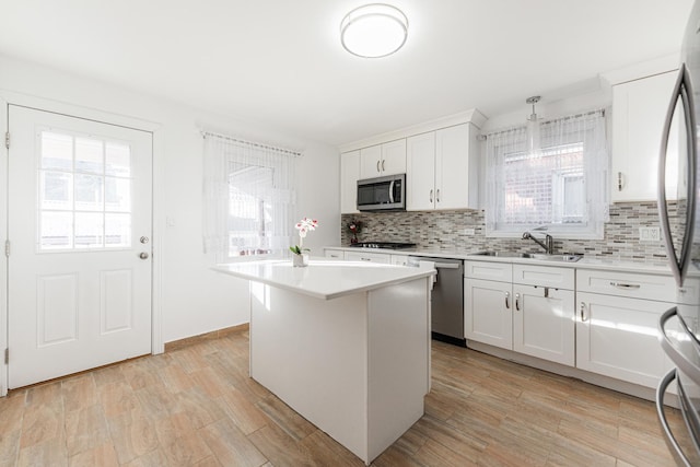 kitchen featuring white cabinetry, a center island, sink, decorative backsplash, and appliances with stainless steel finishes